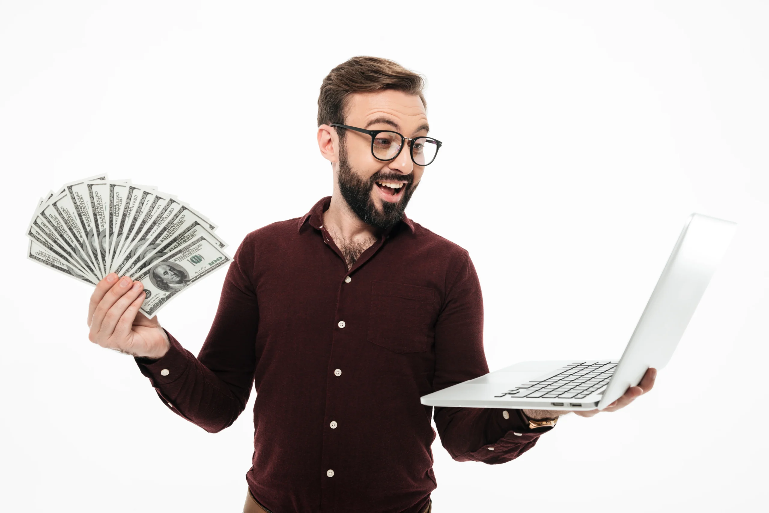 A happy man holding cash and a laptop